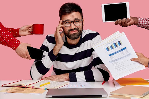 A guy stressed with multiple problems at desk.