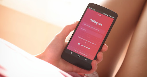 a person holding the phone in her hand and instagram's log-in page is on display.