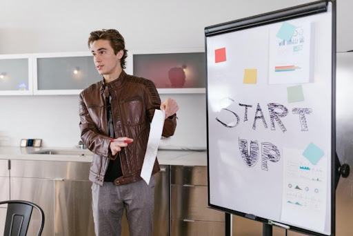 A male employee conducting a meeting using a white board and discussing the buisness.