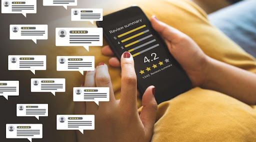 Image of person holding a phone with a home page of "Customer reviews". Reviews are of an app with 4.2 star rating.