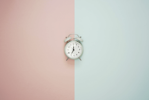 A traditional alarm clock with 2 different coloured backgrounds, indicating sending out emails at different times during the day.